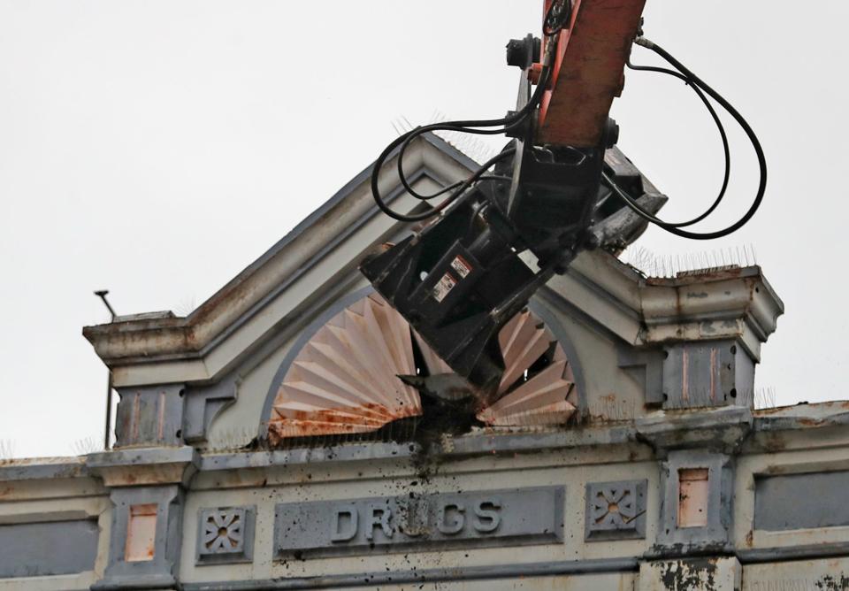 A claw takes down the metal decoration on the top of 14 Lincoln Way E in Massillon on Sunday. Crews worked to demolish the buildings at 14 Lincoln Way E and 20 Lincoln Way E.