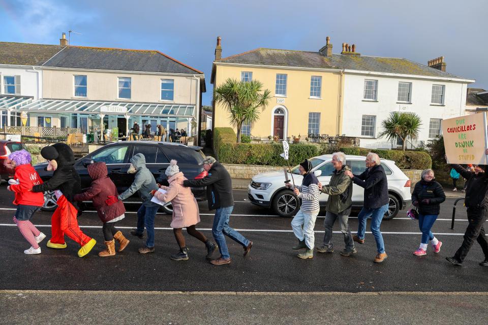 Campaigners Save Our Seafront protest against â€˜wiggly linesâ€™ which have been painted on a road in Clevedon as part of a new layout.
The protest to called â€˜Snake on Sundayâ€™ where demonstrators in fancy dress with homemade banners are â€˜walking the lineâ€™ in a wavy wiggle conga. Members believe the wiggly changes to the Victorian seafront amount to 'vandalism' by the council. Protesters will demand the road is put back to how it was. 15/01/2023