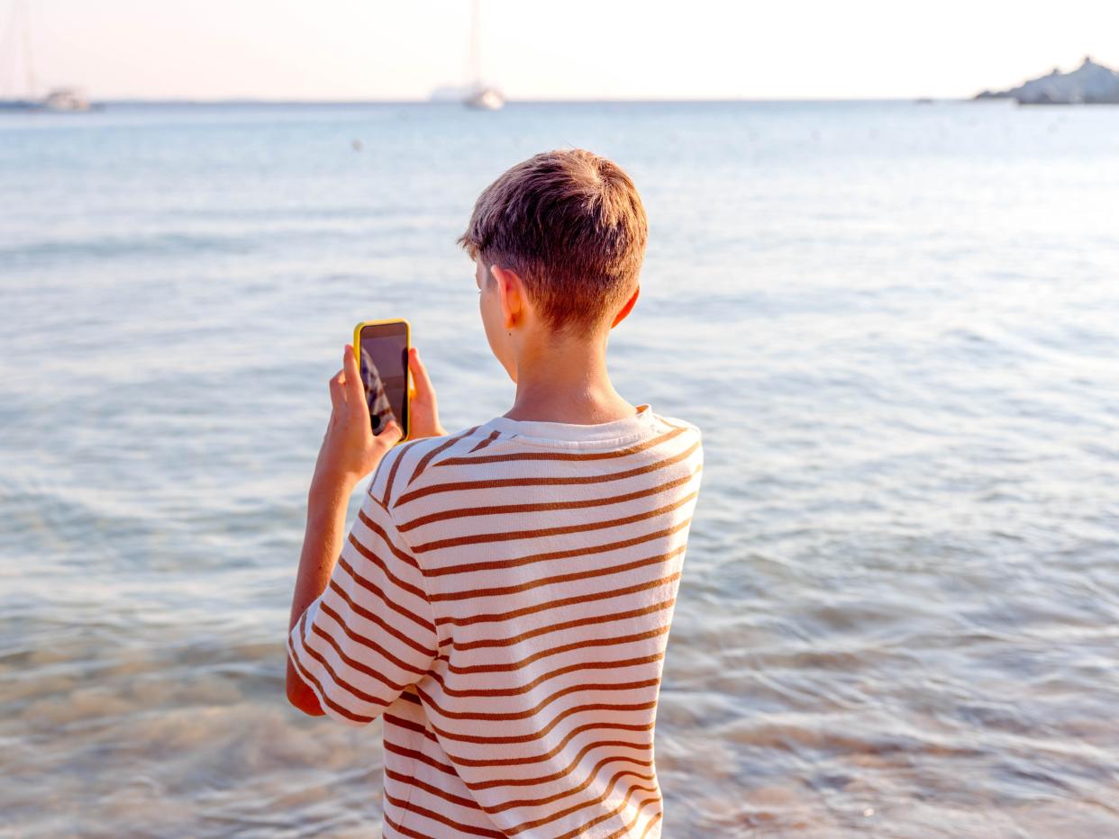 A teenage boy taking photos on a beach