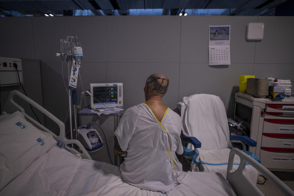 A COVID-19 patient sits on a bed at the new Nurse Isabel Zendal Hospital in Madrid Madrid, Spain, Monday, Jan. 18, 2021. As the coronavirus curve of contagion turned increasingly vertical after Christmas and New Year's, the Zendal has been busy. On Monday, 392 virus patients were being treated, more than in any other hospital in the Madrid region. (AP Photo/Bernat Armangue)