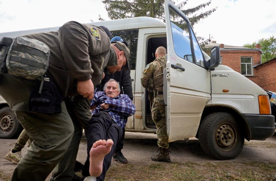 Policemen and volunteers load an elderly man onto a van as they evacuate locals from the Buhaivka village near Volchansk, Kharkiv area (EPA)