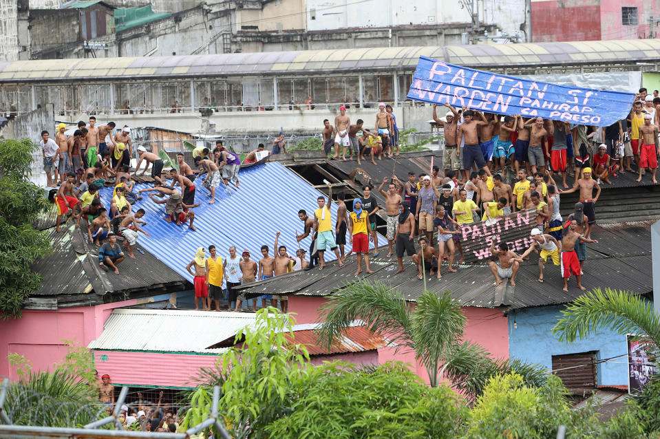 Detainees display huge signs demanding that the prison chief be replaced as they gather on the rooftop of the jail in Manila City Jail in Manila
