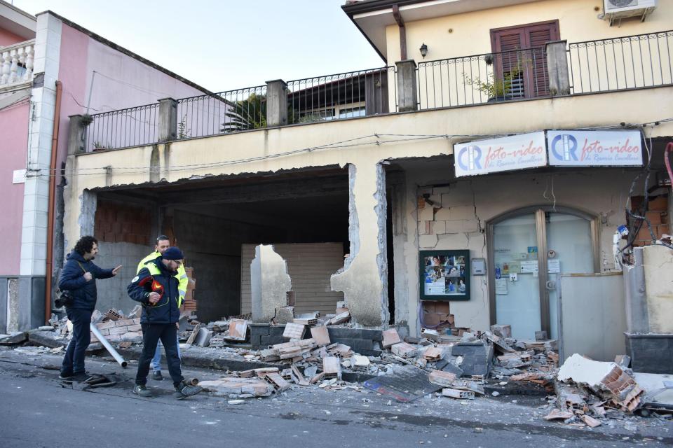 People walk past an heavily damaged house in Fleri, Sicily Italy, Wednesday, Dec. 26, 2018. A quake triggered by Italy's Mount Etna volcano has jolted eastern Sicily, slightly injuring 10 people and prompting frightened Italian villagers to flee their homes. (Orietta Scardino/ANSA Via AP)