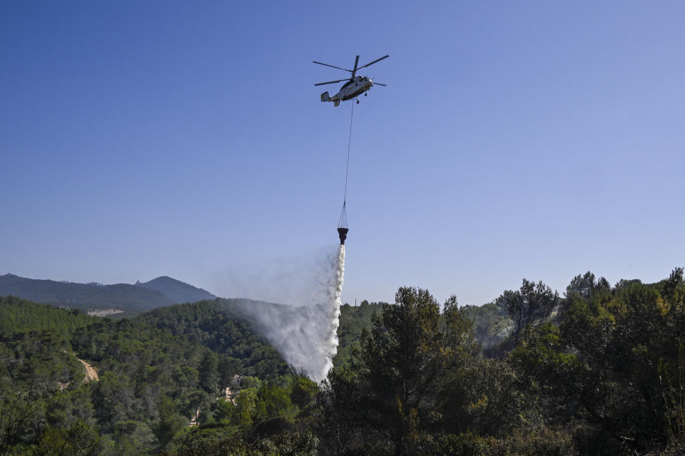 CASCAIS, PORTUGAL - JULY 26: A Kamov 32A11BC firefighting helicopter drops water over smoldering areas in the aftermath of a large forest fire where still on the ground remain 492 firefighters, supported by 190 vehicles and two firefighting helicopters on July 26, 2023 in Cascais, Portugal. A fire with two active fronts in a forest area broke out on July 25 around 4pm in the locality of Zambujeiro, Alcabideche, Cascais Municipality. Vehicles traffic were for hours blocked between the Alvide and Cascais junctions on the A5 highway in both directions. Europe is suffering a wave of forest fires due to high temperatures in the continent. (Photo by Horacio Villalobos#Corbis/Corbis via Getty Images)