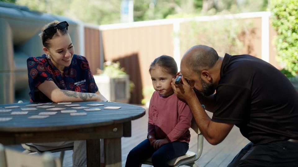 A person performs an ear health check on a child.