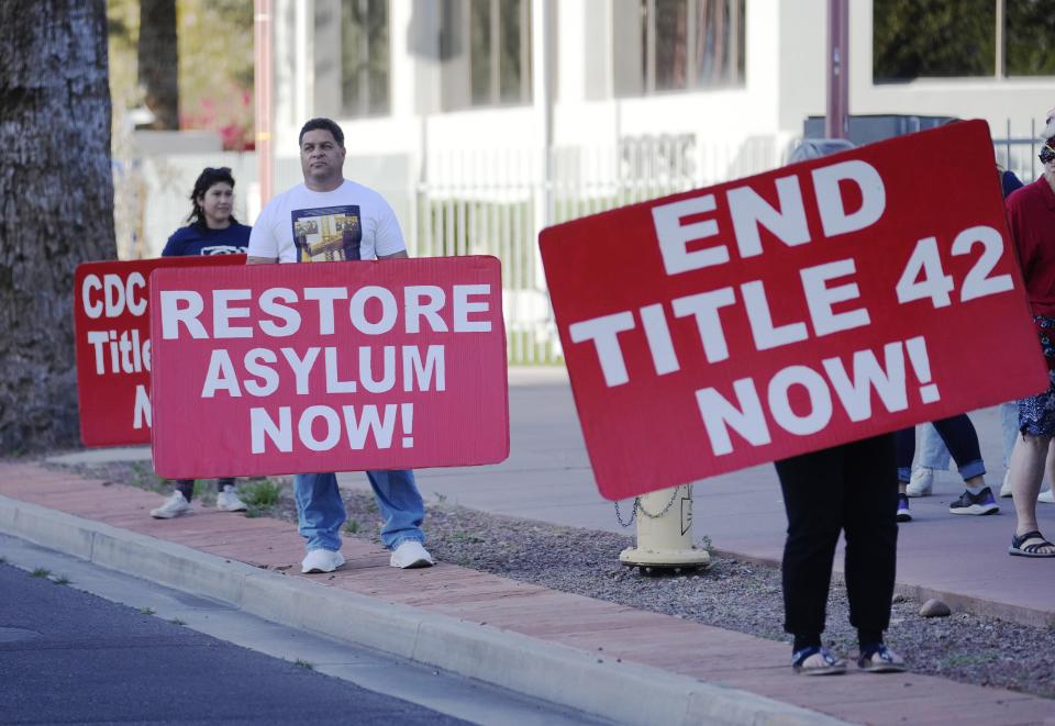 Demonstrators hold signs during a rally for asylum seekers outside the ICE offices in Phoenix on March 22, 2022. They are demanding the Biden Administration end Title 42 and stop holding asylum seekers illegally in Mexico.