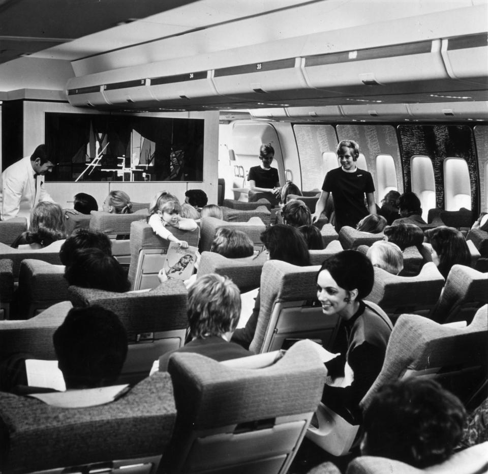 Air stewards aboard BOAC (a predecessor to British Airways) tend to rows of passengers seated in the new Boeing 747 wide-cabined jumbo jet.