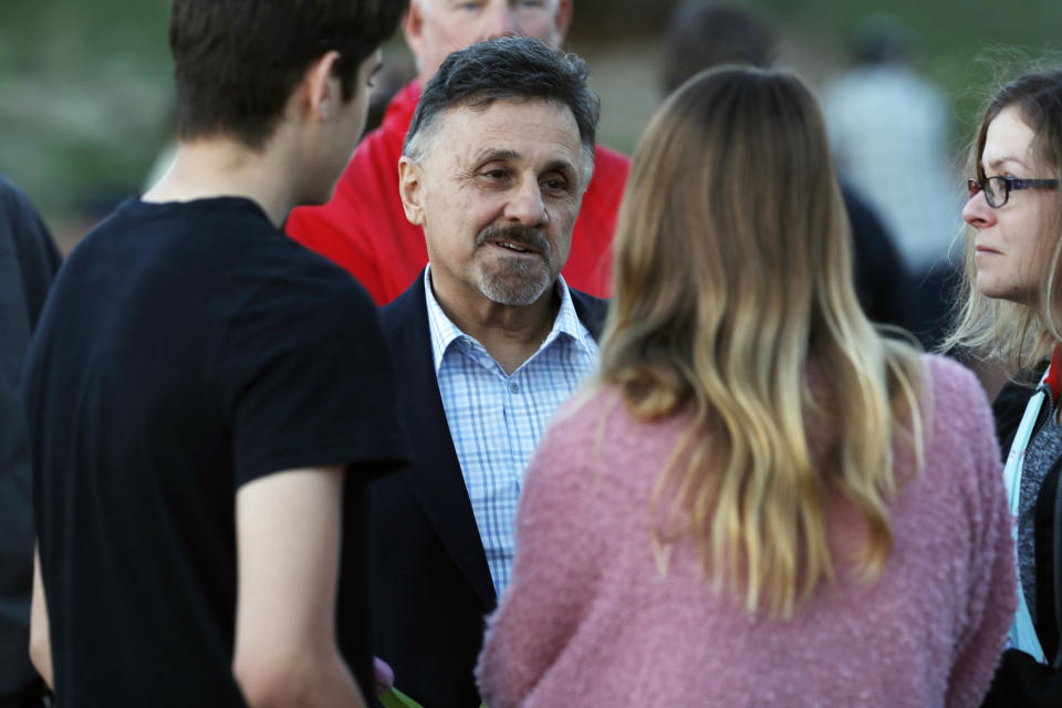 FILE - In this Friday, April 19, 2019, file photograph, Frank DeAngelis, center, greets well-wishers during a vigil at the memorial for victims of the massacre at Columbine High School more than 20 years earlier in Littleton, Colo. DeAngelis was principal of the school at the time of the attack. The school district is considering razing the current building and putting up a new structure. (AP Photo/David Zalubowski, File)