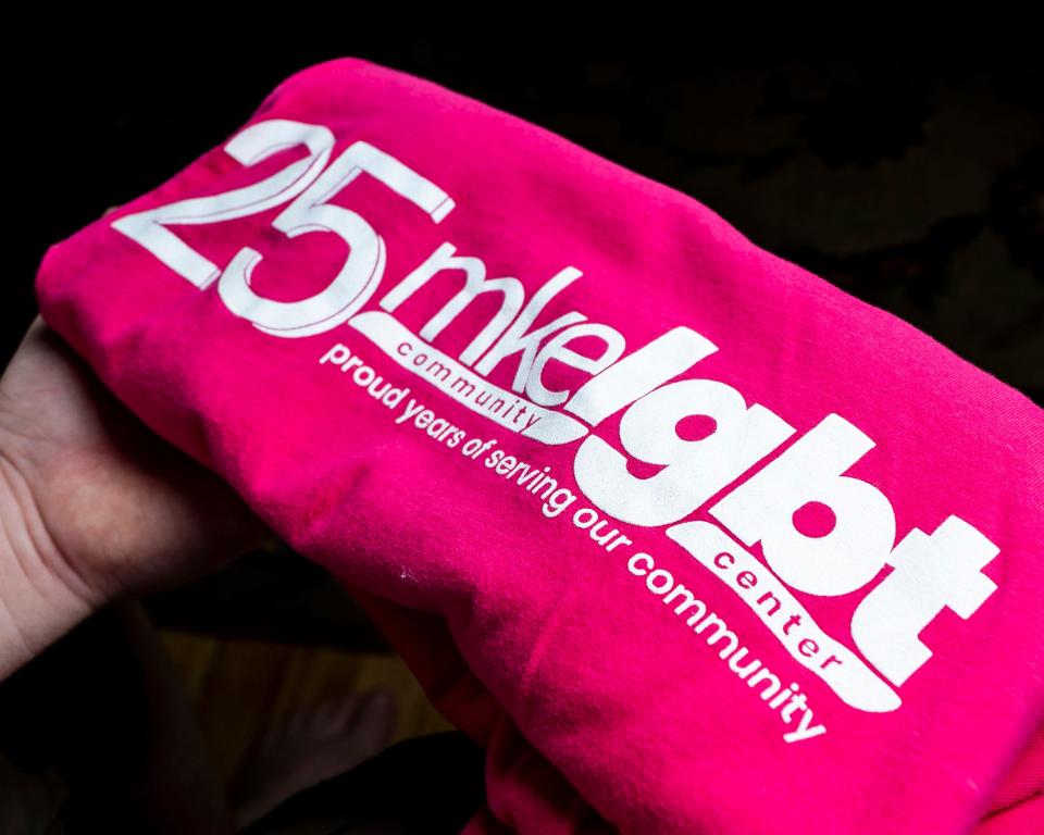 Killian, an 18-year-old trans man, holds a 25-year anniversary shirt from the Milwaukee LGBT Community Center.