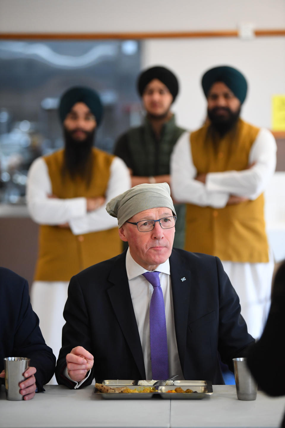 The cap fits for SNP leader John Swinney as he tucks into a curry lunch at the Glasgow Gurdwara (Andy Buchanan/PA)