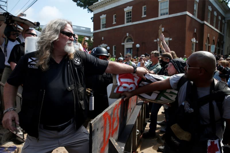 Un suprémaciste blanc agrippe un contre-manifestant dans la foule à Charlottesville. Après les heurts qui ont éclaté samedi, le gouverneur démocrate de Virginie avait déclaré l'état d'urgence et ordonné la dispersion de la manifestation. Dans la soirée, le conseil municipal a voté l'instauration d'un couvre-feu par la police. /Photo prise le 12 août 2017/REUTERS/Joshua Roberts