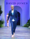 <p>Anwar Hadid couldn’t resis a cheeky smile as he emerged onto the catwalk looking dapper in a blue suit, white logo tshirt and a pair of cool pink runners. Photo: Getty Images </p>