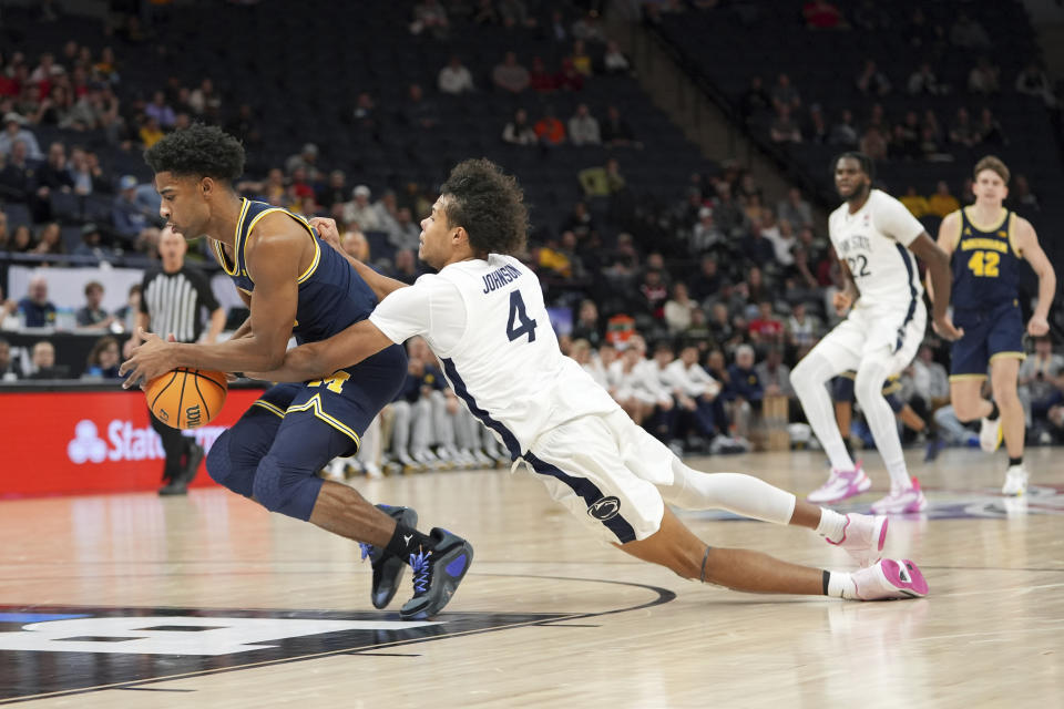 Michigan guard Jace Howard, left, and Penn State forward Puff Johnson (4) scramble for the basketball during the second half of an NCAA college basketball game in the first round of the Big Ten Conference men's tournament Wednesday, March 13, 2024, in Minneapolis. (AP Photo/Abbie Parr)
