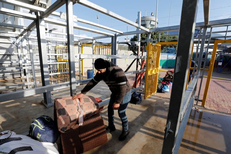 A Palestinian man working in Israel collects his belongings as he heads to work through an Israeli checkpoint, near Hebron in the Israeli-occupied West Bank