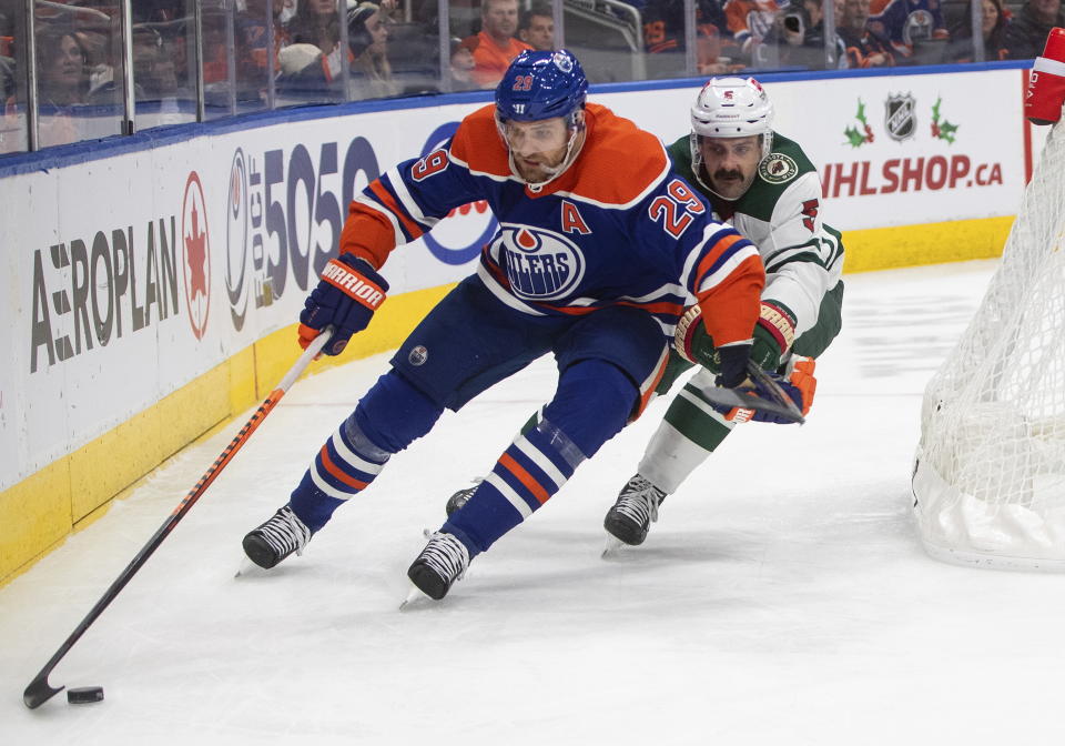 Minnesota Wild's Jacob Middleton (5) and Edmonton Oilers' Leon Draisaitl (29) battle for the puck during second-period NHL hockey game action in Edmonton, Alberta, Friday, Dec. 9, 2022. (Jason Franson/The Canadian Press via AP)