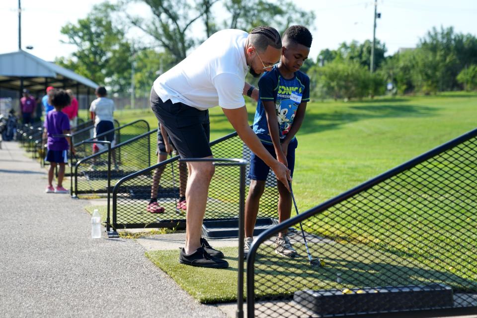 Larry B. Hodge, a la izquierda, de Silverton, trabaja con su hijo, Larry C. Hodge, de 8 años, durante la clínica de golf juvenil organizada por Reaching Out For Kids, Inc., el sábado 22 de julio de 2023, en Avon Fields en el vecindario de Avondale en Cincinnati.