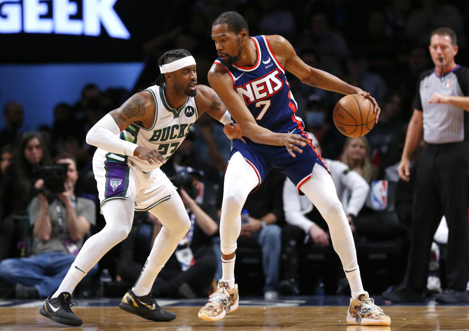 Brooklyn Nets forward Kevin Durant (7) is defended by Milwaukee Bucks guard Wesley Matthews (23) during the first half of an NBA basketball game Thursday, March 31, 2022 in New York. (AP Photo/Noah K. Murray)