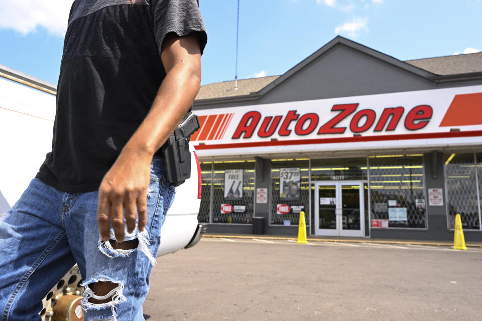 A man carrying a firearm on his hip for protection leaves an Auto Zone store, Thursday, Sept. 8, 2022, in Memphis, Tenn. On Wednesday afternoon, a man entered the Auto Zone and live streamed himself as he shot a person who lived through the incident. Other attacks by the man on the same Wednesday resulted in killing four and wounding three. (AP Photo/John Amis)