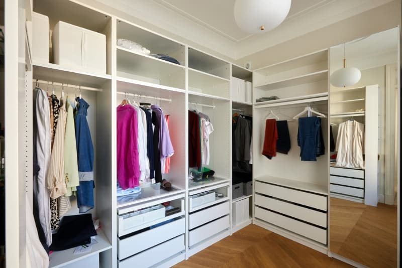 White wardrobe with clothes on hangers at home