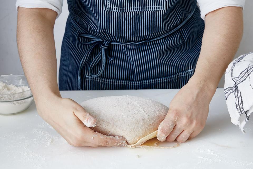 Using a gentle hand, and possibly that bench scraper again, pull the shaped dough toward you to tighten its surface.