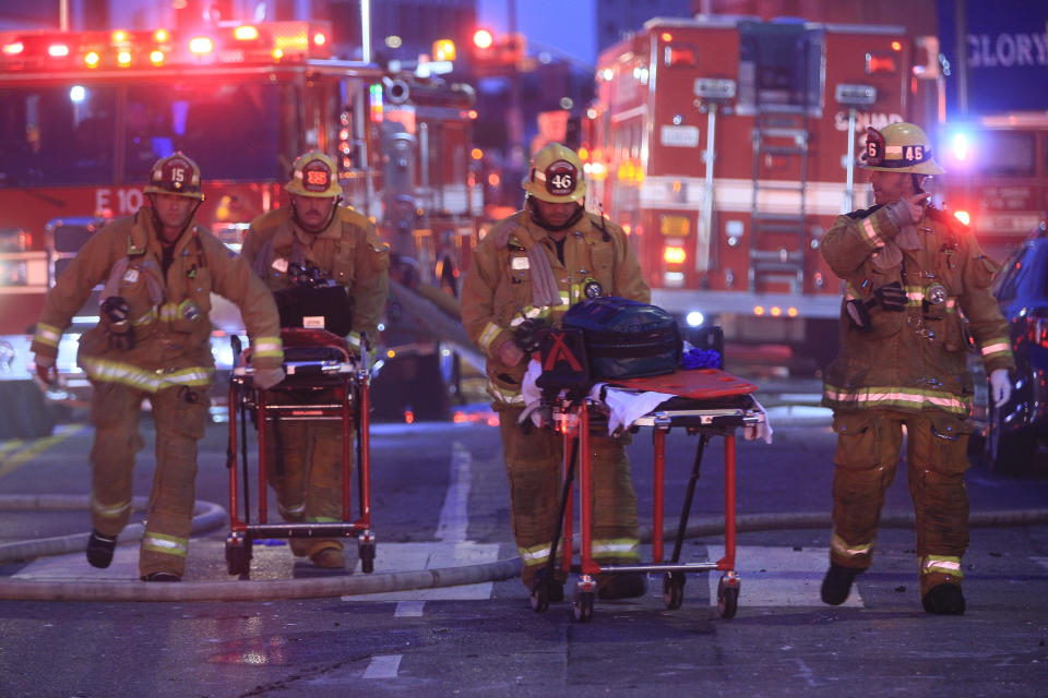 Los Angeles Fire Department firefighters push ambulance cots at the scene of a structure fire that injured multiple firefighters, according to a fire department spokesman, Saturday, May 16, 2020, in Los Angeles. (AP Photo/Damian Dovarganes)