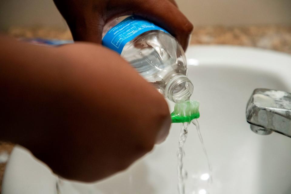 Dearion Jefferson, 13, uses bottled water to brush his teeth in the bathroom of his Pavone Street home he shares with his grandmother in Benton Harbor on Oct. 26, 2021.