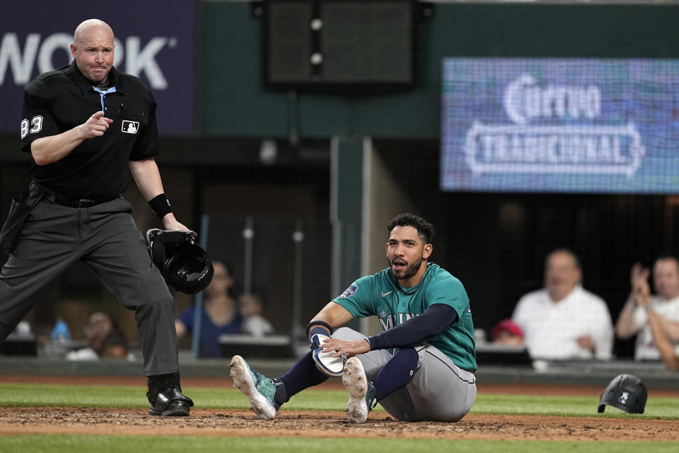 Home plate umpire Mike Estabrook, left, signals after Seattle Mariners' Jose Caballero was called out while trying to score from third in the fourth inning of a baseball game, Saturday, June 3, 2023, in Arlington, Texas. Mariners' Julio Rodriguez stole second base on the same play. (AP Photo/Tony Gutierrez)