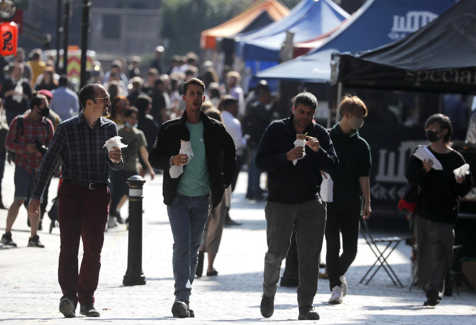 People walk along a street of a food market in London, Monday, Sept. 21, 2020. Britain's top medical advisers have painted a grim picture of exponential growth in illness and death if nothing is done to control the second wave of coronavirus infections, laying the groundwork for the government to announce new restrictions later this week. (AP Photo/Frank Augstein)