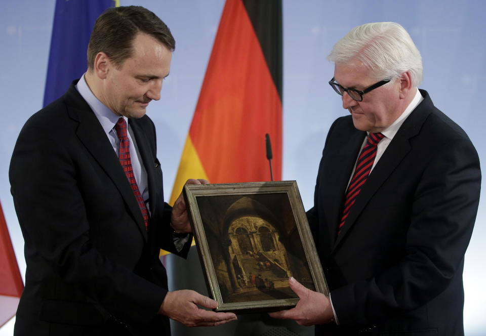 German Foreign Minister Frank-Walter Steinmeier, right, hands over the painting 'Palace Stairs' by 18th-century Venetian artist Francesco Guardi to his counterpart from Poland Radoslaw Sikorski, left, during a ceremony at the Foreign Ministry in Berlin, Germany, Monday, March 31, 2014. The painting was taken from Poland's National Museum in 1939 and after World War II, it passed into the collection of the State Gallery of Baden-Wuerttemberg. (AP Photo/Michael Sohn)