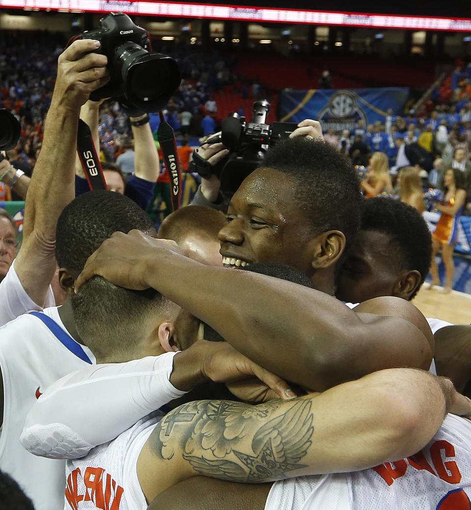 Florida forward Will Yeguete (15) embraces team mates after the second half of an NCAA college basketball game against Kentucky in the Championship round of the Southeastern Conference men's tournament, Sunday, March 16, 2014, in Atlanta. Florida won 61-60. (AP Photo/John Bazemore)