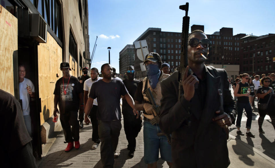 Armed protesters march in downtown St. Louis as a man from a boarded up dry cleaners watches through the doorway after former St. Louis police officer Jason Stockley was acquitted in the shooting death of Anthony Lamar Smith on Friday, Sept. 15. (Photo: Photo by Robert Cohen/St. Louis Post-Dispatch)