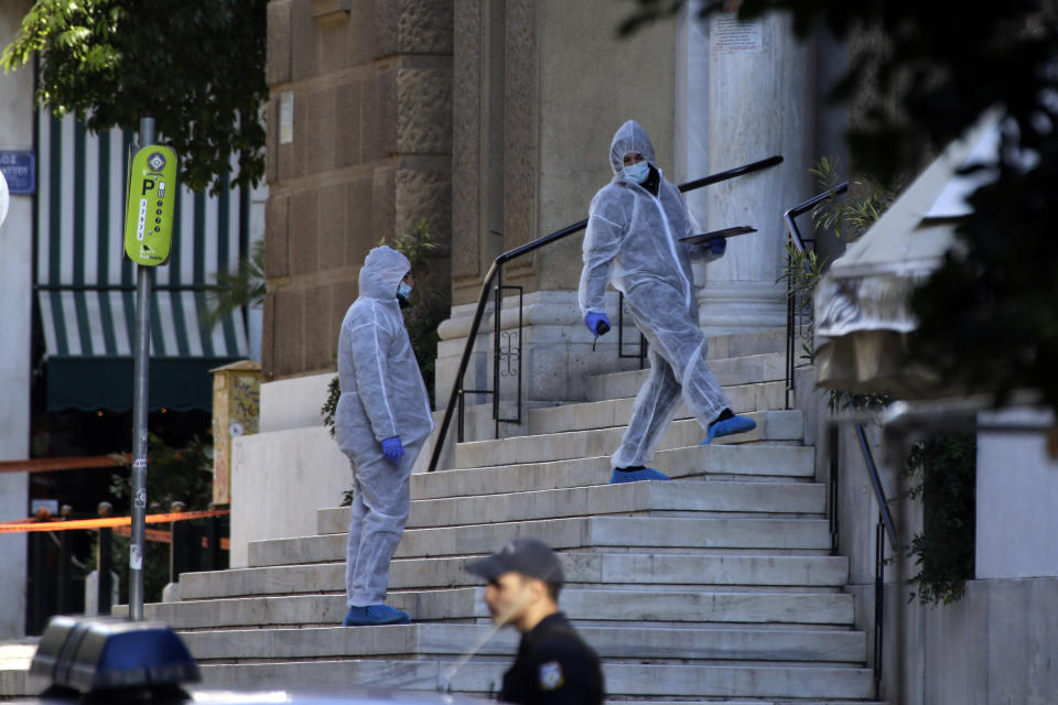 Greek forensic experts search at the scene after an explosion outside the Orthodox church of Agios Dionysios in the upscale Kolonaki area of Athens, Thursday, Dec. 27, 2018. A Greek police officer and a church caretaker were injured in an explosion as they investigated a suspicious package outside a church in central Athens early Thursday. (AP Photo/Thanassis Stavrakis)