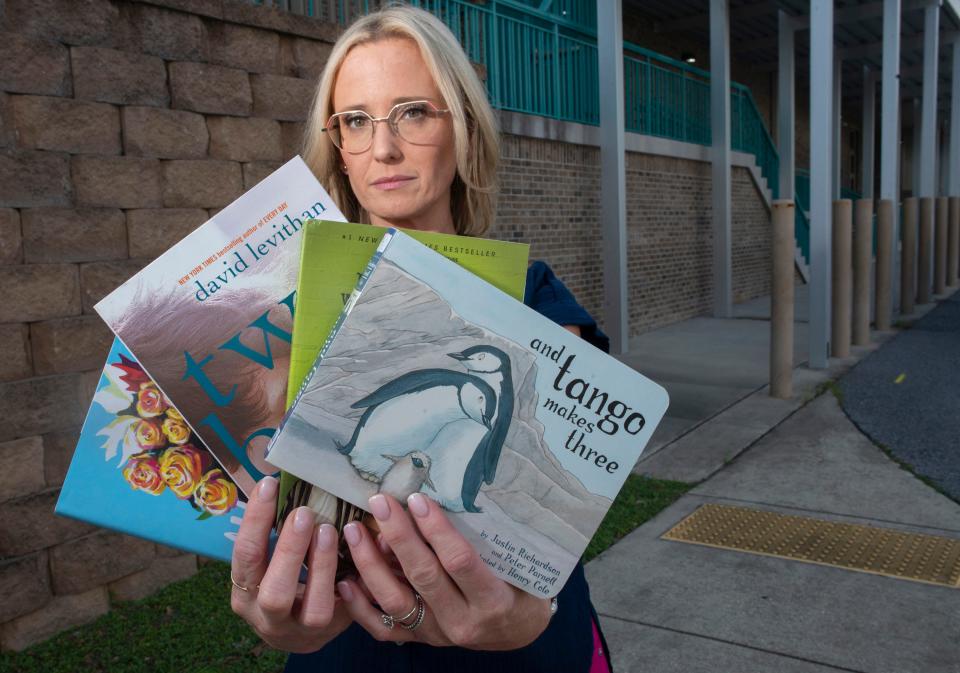 Lindsay Durtschi shows off the books currently banned by the Escambia County school system. Durtschi is part of a lawsuit against the school district and school board over the removal of books from school libraries.