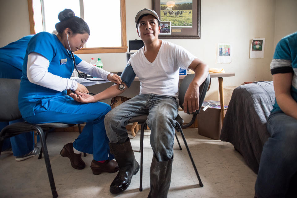 Tecpile gets his blood pressure checked during a health screening with Amaris Vesely, a nursing student from the University of Wisconsin, Eau Claire, at the Rosenholm dairy farm. (Photo: Caroline Yang for HuffPost)