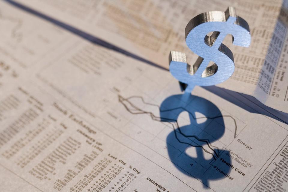 A dollar sign appearing in a financial newspaper with stock prices and charts.