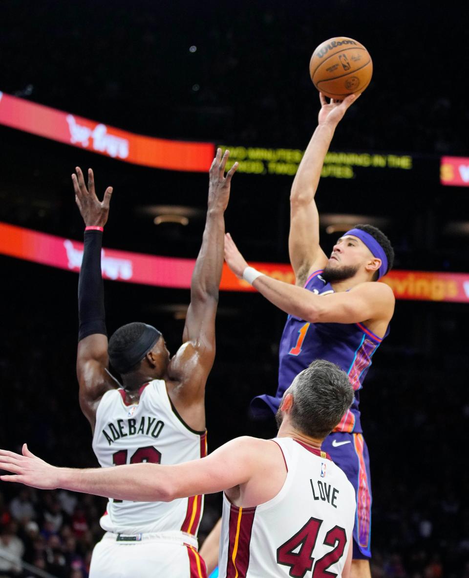 Jan. 5, 2024; Phoenix, Ariz; USA; Suns guard Devin Booker (1) shoots against Heat center Bam Adebayo (13) during the first half at the Footprint Center.