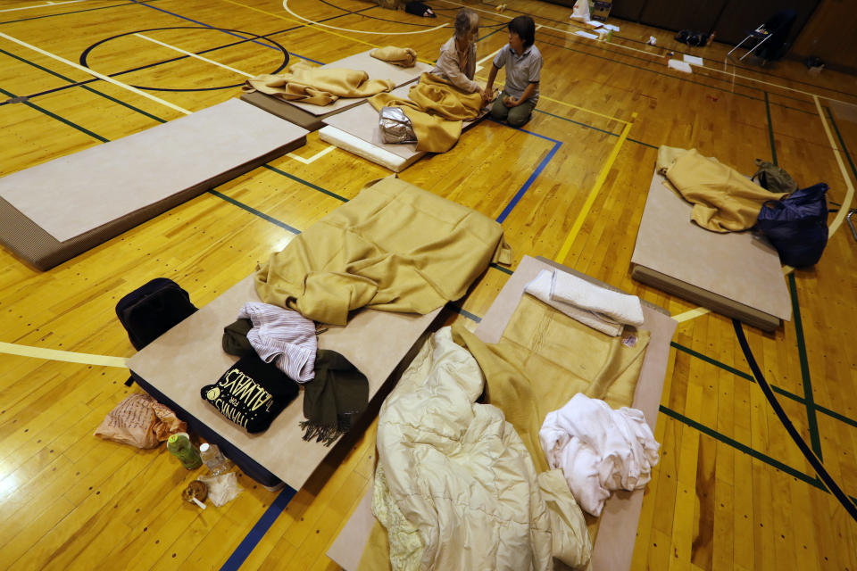 Evacuees from Typhoon Hagibis take shelter at a nearby elementary school gym on Monday, Oct. 14, 2019, in Kawagoe City, Japan. Rescue crews are digging through mudslides and searching near swollen rivers for missing people after Hagibis caused serious damage in central and northern Japan. (AP Photo/Eugene Hoshiko)