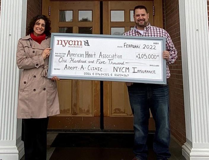 Christine Kisiel, left, and Jeremy Robinson pose recently with a ceremonial check announcing NYCM Insurance&#39;s partnership with the American Heart Association to support Utica-area blood pressure clinics.