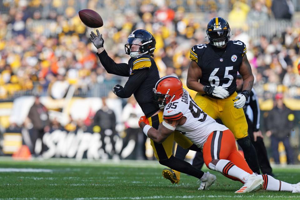 Pittsburgh Steelers quarterback Kenny Pickett, top left, gets off a pass while in the grasp of Cleveland Browns defensive end Myles Garrett (95) during the first half of an NFL football game in Pittsburgh, Sunday, Jan. 8, 2023. (AP Photo/Matt Freed)