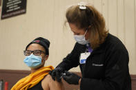 FILE - In this April 13, 2021, file photo, Isis Gardner, left, receives a dose of the Pfizer COVID-19 vaccine at the Banning Recreation Center in Wilmington, Calif. The site switched from its original plan to use the Johnson and Johnson COVID-19 to the Pfizer vaccine. With coronavirus shots now in the arms of nearly half of American adults, the parts of the U.S. that are excelling and those that are struggling with vaccinations are starting to look like the nation’s political map: deeply divided between red and blue states. (AP Photo/Marcio Jose Sanchez, File)