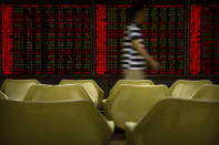 A Chinese investor walks past electronic display boards at a stock brokerage house in Beijing, Tuesday, Aug. 20, 2019. Asian shares were mostly higher Tuesday after Wall Street rallied on the U.S. decision to give Chinese telecom giant Huawei another 90 days to buy equipment from American suppliers. (AP Photo/Mark Schiefelbein)