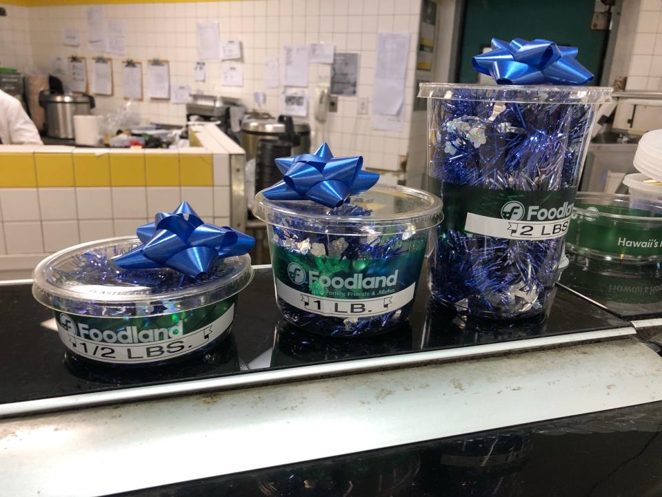 Poke containers with blue bows on top at the seafood counter at Sack N Save in Hilo, Hawaii