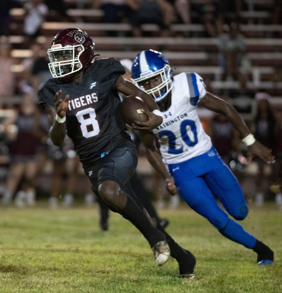 Pensacola High School's quarterback races for open field as Washington High School's Kaleb Campbell (No. 20) gives chase during Friday night's regular season opener