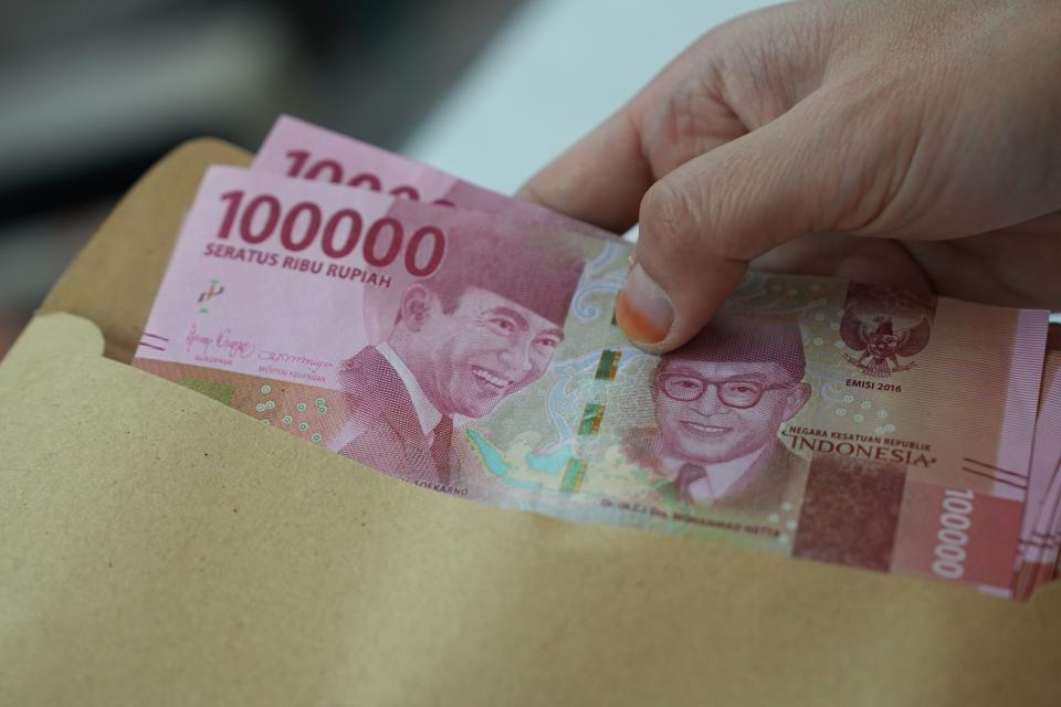 A woman puts Indonesian rupiah banknotes into an envelope at a currency exchange office in Jakarta, Indonesia, on Thursday, Oct. 5, 2023. Photographer: Dimas Ardian/Bloomberg