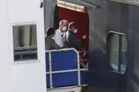 A Broward Sheriff Fire Rescue employee, right, speaks to personnel on the gangplank of the cruise ship Rotterdam as passengers wait to disembark at Port Everglades, Thursday, April 2, 2020, in Fort Lauderdale, Fla. (AP Photo/Wilfredo Lee)