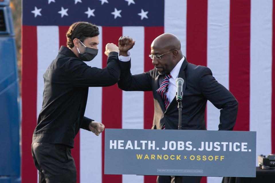 Georgia Democratic Senate candidates Raphael Warnock, right, and Jon Ossoff headline a drive-in voting rally on Dec. 28, 2020, in Stonecrest, Ga.