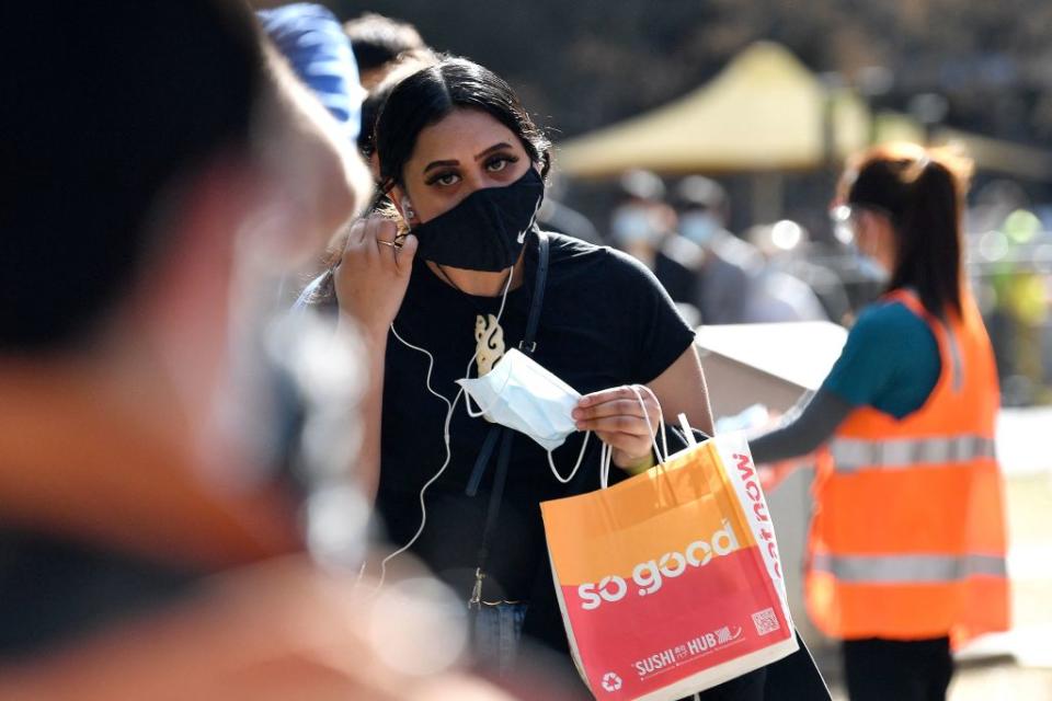 A girl adjusts her mask as she waits in a queue for Covid-19 coronavirus vaccination in Sydney.