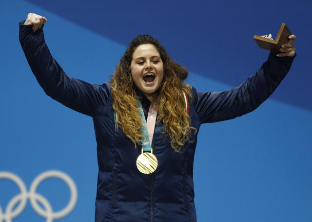 FILE - Women's snowboardcross gold medalist Michela Moioli, of Italy, celebrates during the medals ceremony at the 2018 Winter Olympics in Pyeongchang, South Korea, Friday, Feb. 16, 2018. Defending Olympic gold medalists Sofia Goggia and Michela Moioli both come from the Bergamo area that was the first epicenter of COVID-19 in Europe. Goggia skis with a design of Bergamo's skyline on the back of her racing helmet. Moioli lost her grandmother to the virus. (AP Photo/Patrick Semansky, File)