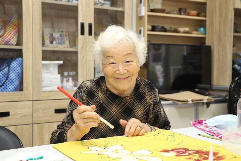 《圖說》滿頭銀絲82歲的林美珠在建德社區青花瓷班彩繪許願藤花。〈社會局提供〉