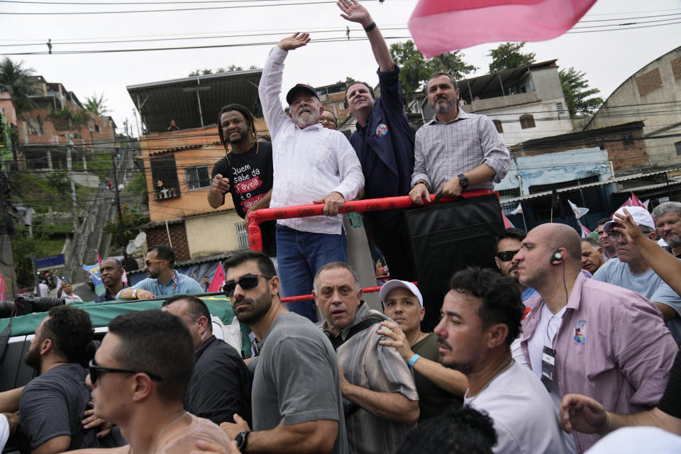 Brazil's former President Luiz Inacio Lula da Silva, who is running for office again, top, second from left, campaigns through the Complexo do Alemao favela in Rio de Janeiro, Brazil, Wednesday, Oct. 12, 2022. The presidential run-off election is set for Oct. 30. (AP Photo/Silvia Izquierdo)